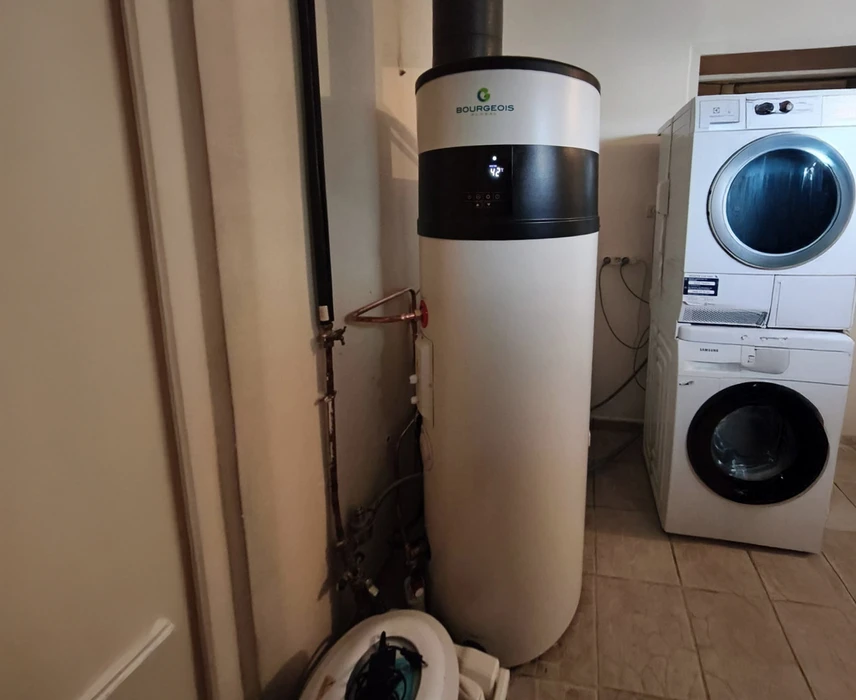 Intérieur d'une buanderie avec technicien installant un chauffe-eau thermodynamique