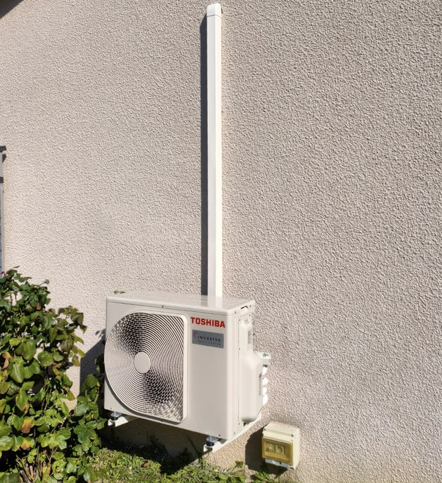 Extérieur d'un bâtiment résidentiel avec unité extérieure de climatisation Toshiba installée sur support mural