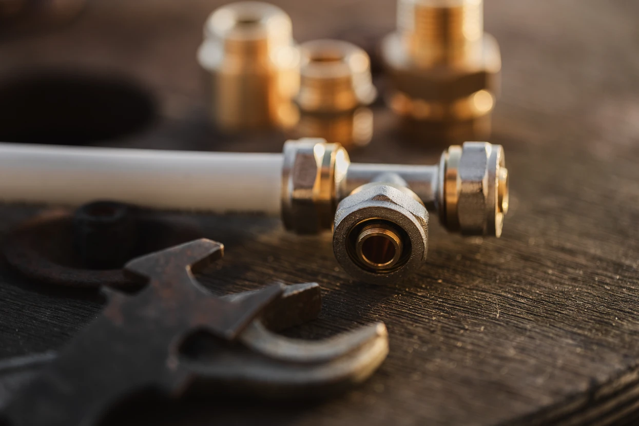 Atelier de plomberie avec raccords en laiton et outils professionnels disposés sur établi en bois
