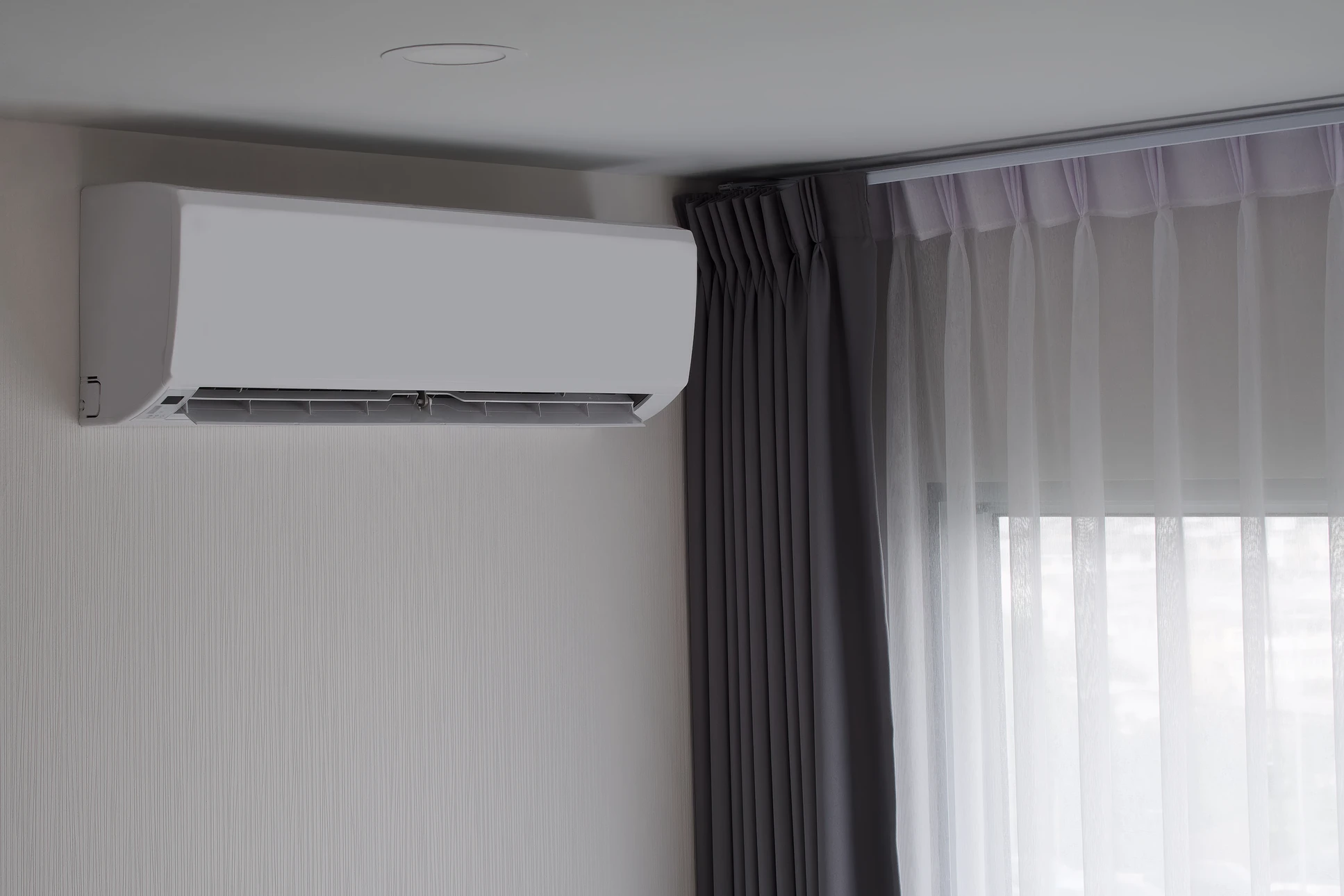 Une femme se détend dans un salon moderne sous un climatiseur mural en fonctionnement, diffusant de l'air frais visible